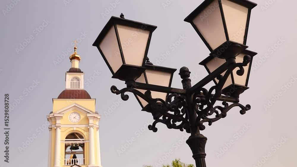Poster a street light with a clock tower in the background, perfect for use in cityscape or urban planning 