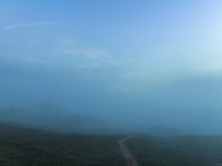 aerial view a sea of white mist envelops the mountain peak, slowly flowing down from the mountain...