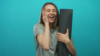 Woman holding yoga mat over isolated green background, showcasing surprise and excitement, ideal...