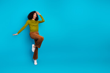 Cheerful young woman in colorful retro-style clothes posing creatively against a bright blue background