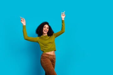 Cheerful woman in casual fashion celebrating against vibrant blue background expressing joy with...