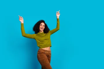 Gordijnen Cheerful woman in casual fashion celebrating against vibrant blue background expressing joy with raised arms © deagreez