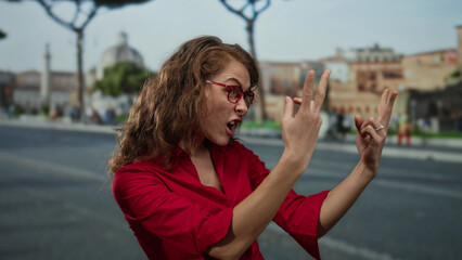 Woman in red shirt making expressive gestures on urban street with historical buildings, demonstrating an emotional reaction outdoors in a city setting