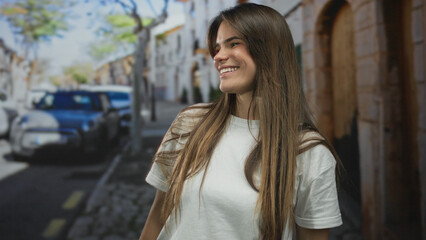 Woman smiling on a bustling city street with vintage cars under a clear blue sky, capturing the lively urban atmosphere with a sense of carefree joy.