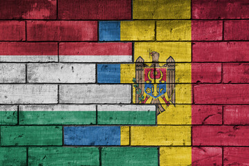colourful painted big national flag of moldova and flag of hungary on a massive old brick wall background. concept