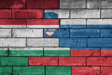 colourful painted big national flag of slovenia and flag of hungary on a massive old brick wall background. concept