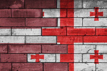 colourful painted big national flag of georgia and flag of latvia on a massive old brick wall background. concept