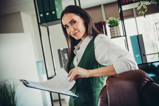 Confident businesswoman holding documents in an elegant office setting, embodying professionalism and success