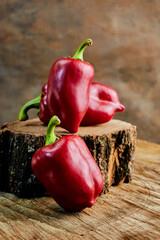 Still life of three sweet bell peppers lying on a stump, ideal for the concept of naturalness,...