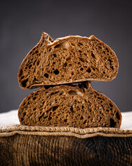 Two half of rye sourdough bread in section on a rustic wooden board. Artisan farmhouse-style loaf captured in warm natural lighting