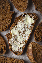 Top view of artisan sliced rye sourdough bread with butter close up. Simple breakfast on grey concrete table