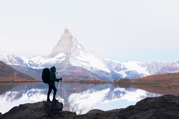 Silhouette of a tourist with a backpack against the background of Matterhorn peak and Stellisee lake in Swiss mountains. Travel and adventure concept