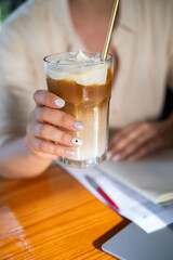 A woman with a relaxed demeanor savors a large cup of cheese latte in a charming cafe. She is...