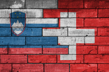 colourful painted big national flag of switzerland and flag of slovenia on a massive old brick wall background. concept