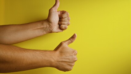 Hands showing thumbs up against a vibrant yellow background displaying positivity, encouragement,...