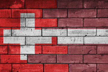 colourful painted big national flag of latvia and flag of switzerland on a massive old brick wall background. concept