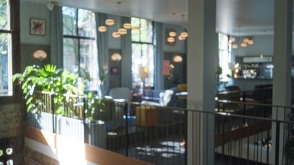 Defocused and illuminated luxury hotel lobby showcases contemporary furniture and vibrant plants, emanating an inviting and warm atmosphere in a spacious elegant setting.