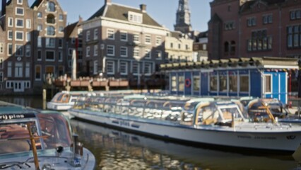 Blurred view of amsterdam canals with iconic dutch buildings and boats, showcasing defocused architecture under a clear sky, capturing the essence of the netherlands' canal cityscape.
