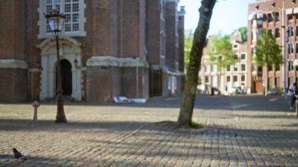 Fototapeta premium Blurred european cobblestone square outside historical church with bokeh effect capturing defocused urban charm and architectural details on a sunny day.