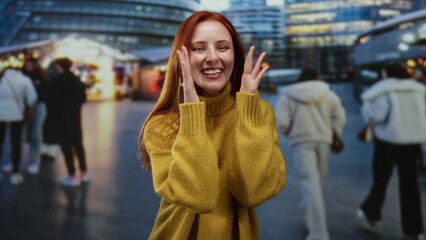 Woman laughing on a bustling city street at night, wearing yellow sweater, surrounded by blurred urban lights and people, conveying a joyful and vibrant scene outdoors.