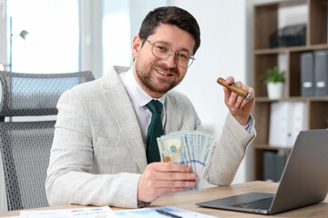 Happy greedy banker with dollar banknotes and cigar at table in office