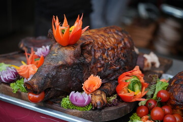 Roasted pork garnished with various fruits and vegetables