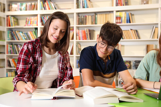 Students with books studying together at table in library
