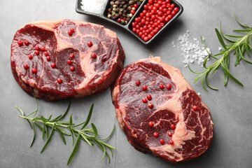 Pieces of raw beef meat and spices on gray textured table, flat lay