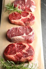 Pieces of raw beef meat, rosemary and salt on table, above view