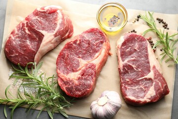 Pieces of raw beef meat and spices on grey table, flat lay