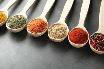 Many different spices in spoons on grey table, closeup