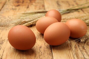 Fresh eggs and spikes on wooden table, closeup