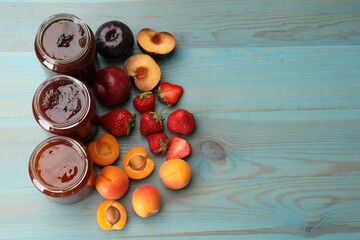 Different jams in jars and ingredients on blue wooden table, flat lay. Space for text