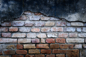 Close up of weathered orange brick wall with rough, aged texture and cracks. Old facade texture used in retro industrial backgrounds and wall surfaces