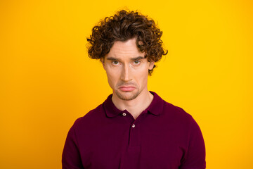 Young man with thoughtful expression posing on a bright yellow background in casual style