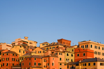 Boccadasse village in Genoa with vivid seaside houses lit by warm sunset tones. Historic Italian coastal scene ideal for travel and architecture photography