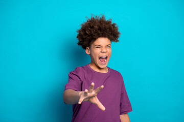 Excited young boy in casual purple t-shirt posing with dynamic gestures against a vibrant blue background