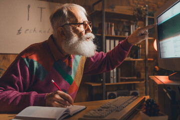 Elderly man engaging in evening programming with a retro computer setup in a cozy home office...