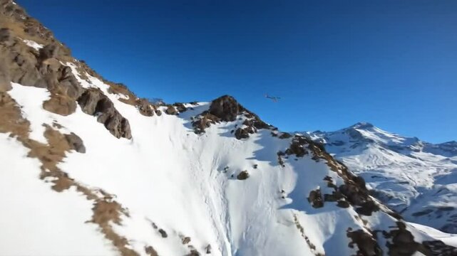Aerial view of snowy mountain range with drone flying under bright sun on a clear blue sky day