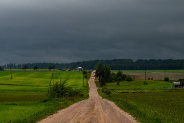 WEATHER - Dramatic black rain clouds over fields and country road.