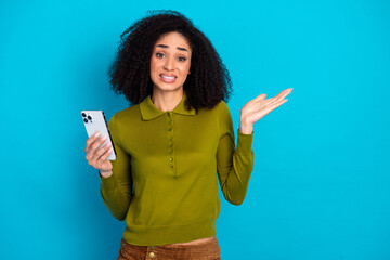 Young woman in casual fashion holding a smartphone, expressing a confused gesture in front of a...
