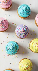 Colorful cupcakes with sprinkles on a white wooden table, top view, bright lighting, stock photography style