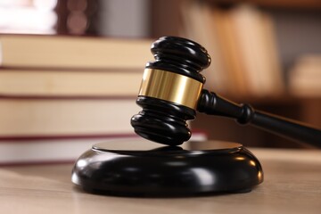 Judge's gavel and books on wooden table indoors, selective focus