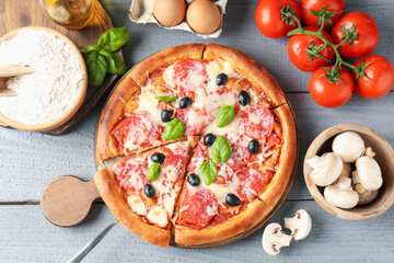 Tasty pizza and ingredients on grey wooden table, flat lay