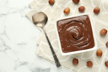 Tasty chocolate spread and hazelnuts on table, flat lay. Space for text