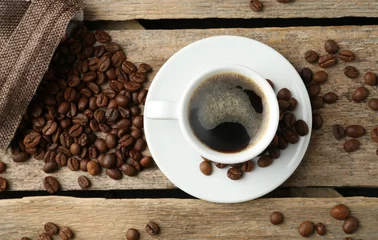 Aromatic coffee in cup and beans on wooden table, flat lay