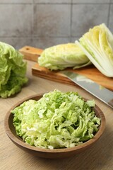 Fresh Chinese cabbages and knife on wooden table, closeup