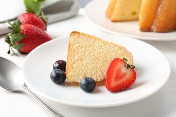 Piece of tasty bundt cake with berries and mint on white table, closeup