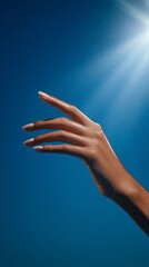 Elegantly Outstretched Hand Reaching Towards Sunlight in Bright Blue Sky Background