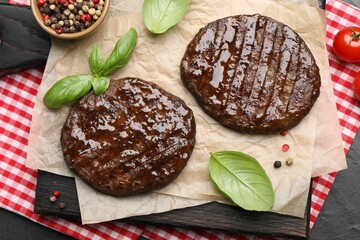 Delicious hamburger patties and spices on black table, top view